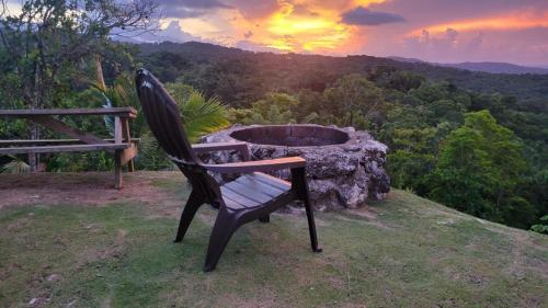 une chaise assise à côté d'un foyer extérieur avec un coucher de soleil dans l'établissement Nonsuch Falls - Journey to Paradise - Modern Waterfall Escape, à Breastworks