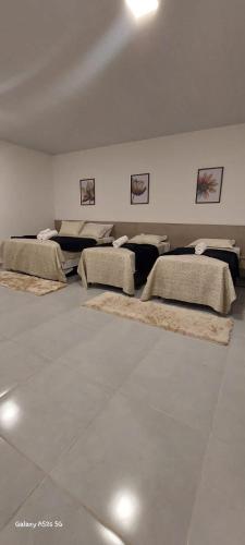 a room with four beds and rugs on the floor at POUSADA ACONCHEGO MT in Chapada dos Guimarães