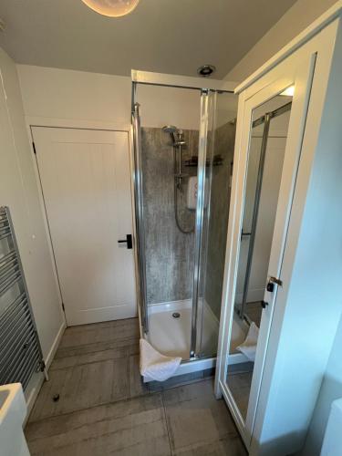 a shower with a glass door in a bathroom at The Mail Barn Studio in Lamlash