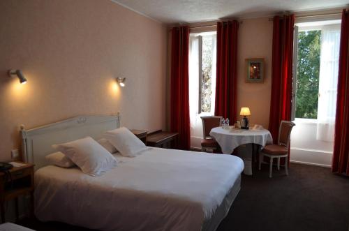 ein Hotelzimmer mit einem großen Bett und einem Tisch in der Unterkunft Hotel de Bourgogne in Cluny