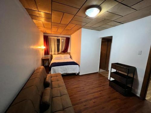 Habitación con sofá y cama. en Hotel El Morlaco, en Cuenca