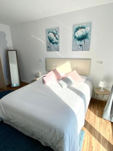 a bedroom with a bed with white sheets and pink pillows at Apartamentos LAMAROSA -LAS PLAYAS in Burela de Cabo