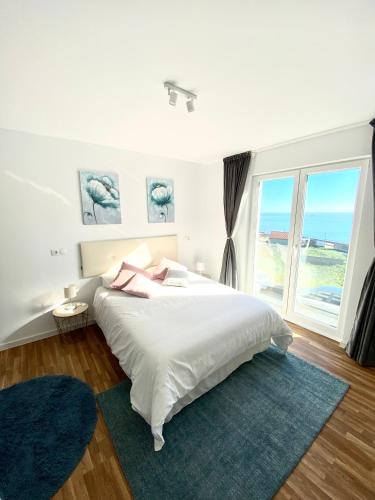 a white bedroom with a large bed and a large window at Apartamentos LAMAROSA -LAS PLAYAS in Burela de Cabo