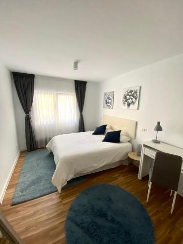 a bedroom with a white bed and a desk and a bed sidx sidx at Apartamentos LAMAROSA -LAS PLAYAS in Burela de Cabo