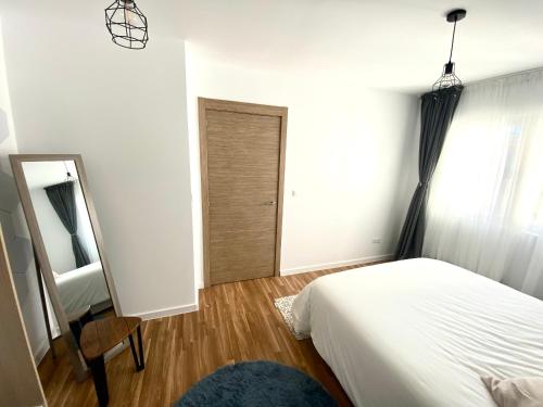 a bedroom with a bed and a mirror and a chair at Apartamentos LAMAROSA -LAS PLAYAS in Burela de Cabo