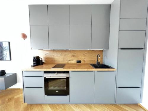 a kitchen with white cabinets and a sink at Stylische Wohnung mit Balkon in Graz