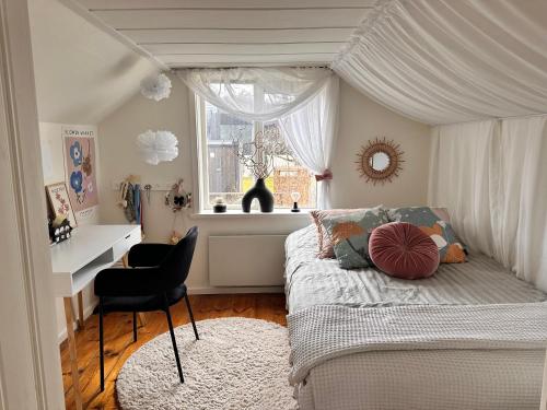 ein Schlafzimmer mit einem Himmelbett, einem Stuhl und einem Fenster in der Unterkunft Havsnära boende Grötvik in Halmstad