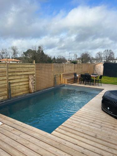 una piscina con una terraza de madera y una valla de madera en Aux portes de bordeaux Maison cocooning avec Piscine spa chauffé, en Ambarès-et-Lagrave