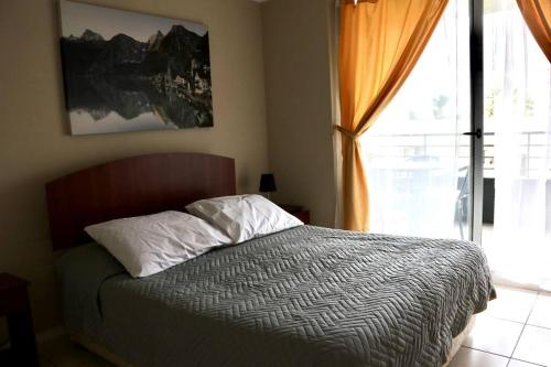 a bedroom with a bed and a large window at Confortable depto. en La Serena in La Serena