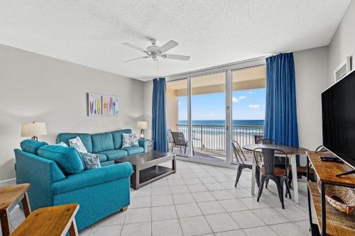 Majestic Beach Resort, Panama City Beach, Fl في بنما سيتي بيتش: غرفة معيشة مع أريكة زرقاء وطاولة طعام مطلة