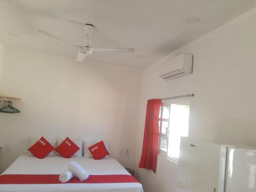 a bedroom with a bed with red pillows and a window at Hotel y Bungalows Bugambilias in San Patricio Melaque