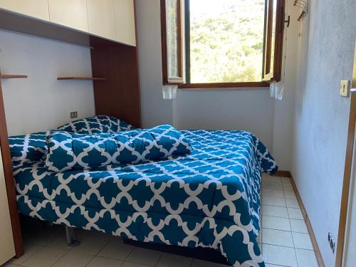 a bedroom with a bed with a blue comforter and a window at Sunlight Apartment in Procchio