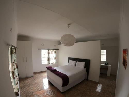 a bedroom with a white bed and two windows at Jacobsen Bungalow in Maun, Boronyane in Maun