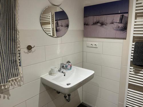 uma casa de banho branca com um lavatório e um espelho em Ferienhaus Sonnenblick an der Nordsee em Epenwöhrden