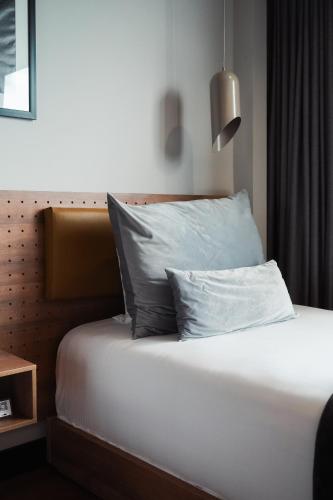 a bed with two pillows on it in a room at Hotel Sexto by Icono in Armenia