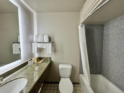 a bathroom with a toilet and a sink and a tub at Days Inn by Wyndham Van Horn TX in Van Horn