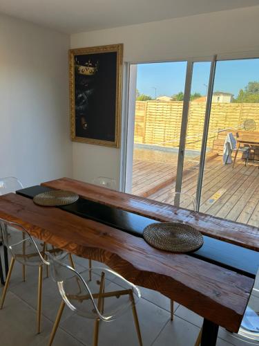 - une table en bois dans une chambre avec vue sur une terrasse dans l'établissement Aux portes de bordeaux Maison cocooning avec Piscine, à Ambarès-et-Lagrave