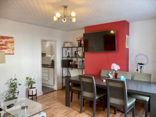 a living room with a dining table and a red wall at Cosy Modern Family Home Free Parking Garden in London