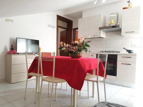 a kitchen with a table with a red table cloth at Appartamenti Cangini in Cesenatico