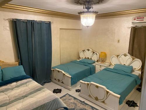 a bedroom with two beds and a chandelier at LuXury Apartment Nasr City - CityStars in Cairo