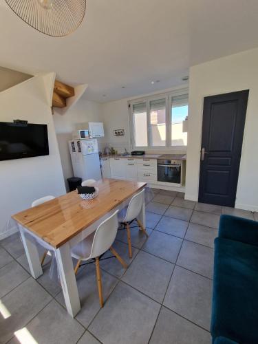 une cuisine et une salle à manger avec une table et des chaises en bois dans l'établissement maisonnette, à Dieppe