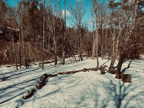 una pila de rocas en la nieve junto a los árboles en NEW Scandi Ski House! Farmhouse, Hot Tub, en Andover