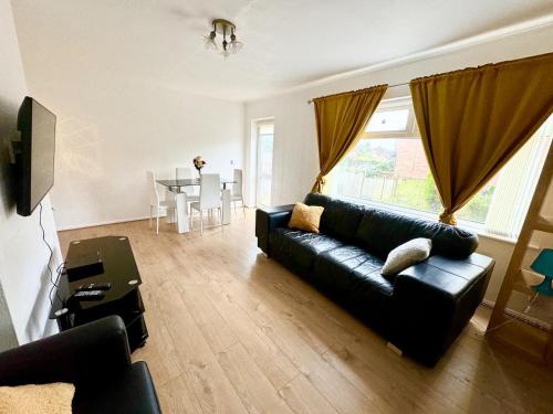 a living room with a black couch and a table at Cosy & Quiet House close to Etihad and City Centre in Manchester