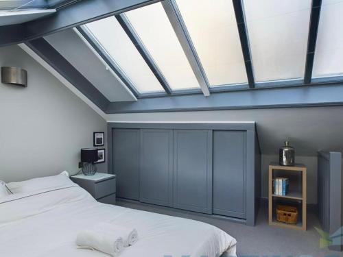 a bedroom with a white bed and a skylight at Spacious open planned 1 bedroom apartment in Burgess Hill