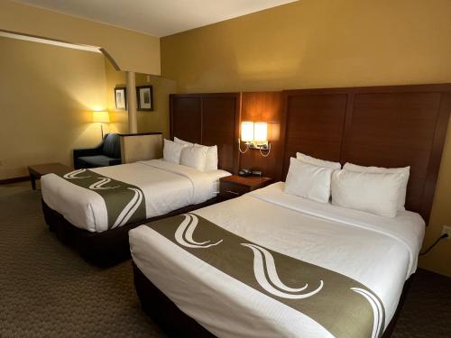 a hotel room with two beds and a chair at Quality Suites Midland North Loop 250 in Midland