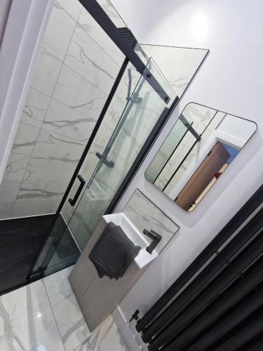 a glass bathroom with a sink and a mirror at Bryn Glo Cottage in Capel Curig