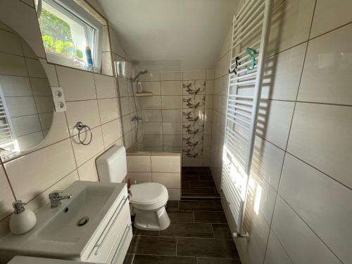 Baño blanco con aseo y lavamanos en Hídláb Apartman, en Kimle
