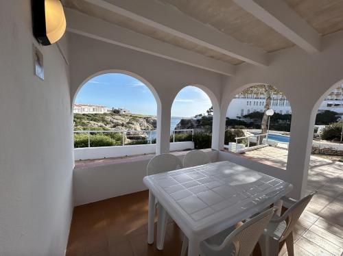 comedor blanco con mesa y vistas al océano en Apartamentos Islanders en Cala en Forcat