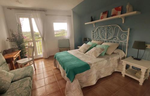 a bedroom with a bed with green sheets and a couch at Hotel Villanueva San Jorge de Heres in Villanueva