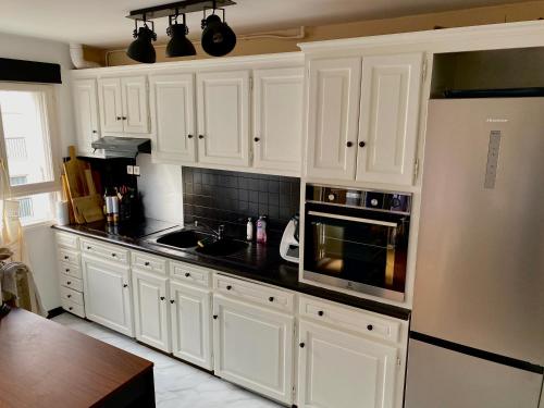 une cuisine avec des armoires blanches et des comptoirs noirs dans l'établissement Appartement rénové et aux portes de Paris !, à Nanterre