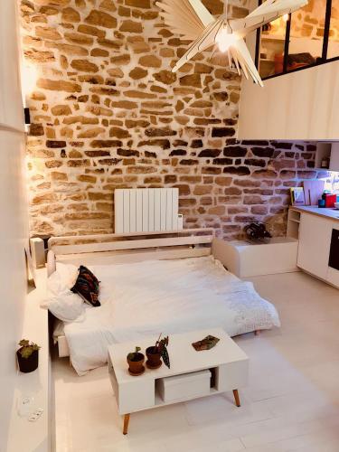 une chambre avec un lit et un mur de briques dans l'établissement Plein cœur de Paris : Charmant Duplex à Bastille, à Paris