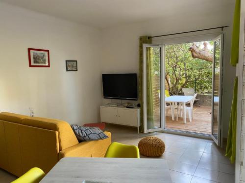 uma sala de estar com um sofá, uma televisão e um pátio em Joli studio avec parking à 2 min à pied de la plage em Argelès-sur-Mer
