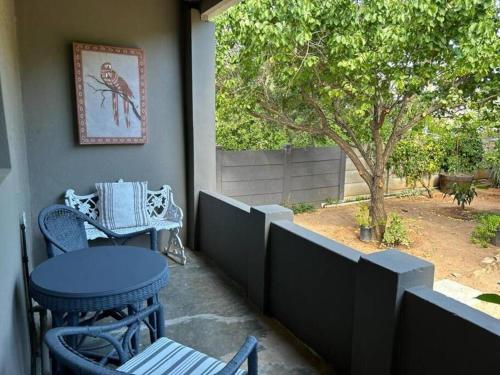 a porch with two chairs and a table and a tree at Hoekhuis in De Rust