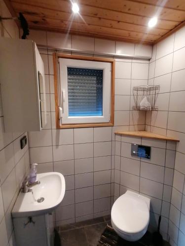 a bathroom with a toilet and a sink and a window at Fala - Domki do wynajecia in Zagórze Śląskie