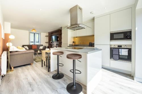 a kitchen and living room with a counter and stools at Rest&Recharge at Brookdale House (5 Bedrooms, 15mins to City Centre, Free Parking) in Manchester