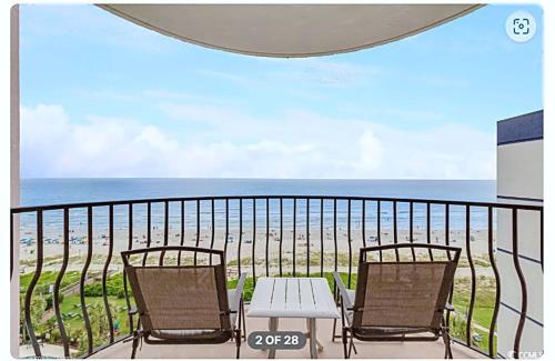 a balcony with two chairs and a table and the beach at Lifes a beach on Myrtle Beach in Myrtle Beach