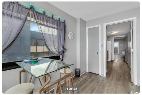 a dining room with a glass table and a window at Lifes a beach on Myrtle Beach in Myrtle Beach