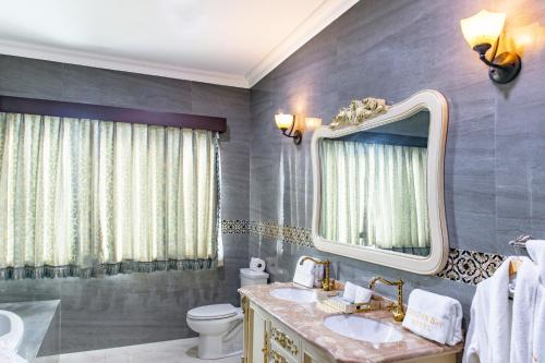 a bathroom with a sink and a mirror and a toilet at Golden Bay Belize Hotel in Belize City