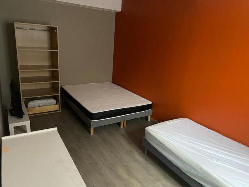 Cette chambre comprend 2 lits et un mur orange. dans l'établissement Appartement 4 - Hyper centre - 1 à 4 personnes, à Douai