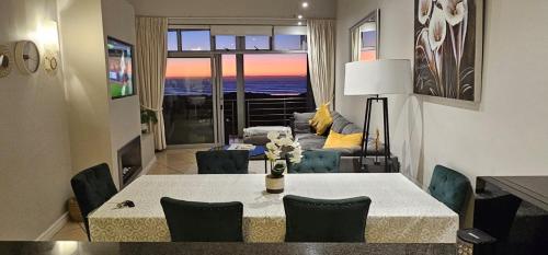 - un salon avec une table, des chaises et un canapé dans l'établissement Beachfront 3-bedroom with Robben Island views, au Cap