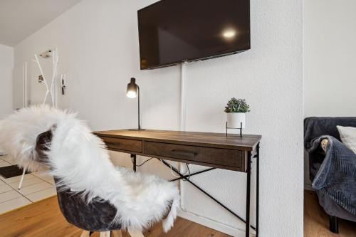 a white dog standing on a chair in front of a desk at Comfort Family & Business Apartment in Neunkirchen - 2 SZ - bis zu 5 Pers - Balkon - Badewanne - WLAN 250 Mbit - Parkplatz - Self-Check-in in Neunkirchen