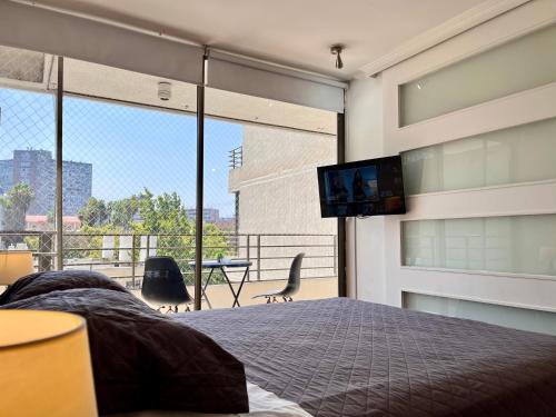 um quarto com uma cama e uma televisão na parede em Apartamentos City Centro Manuel Montt em Santiago