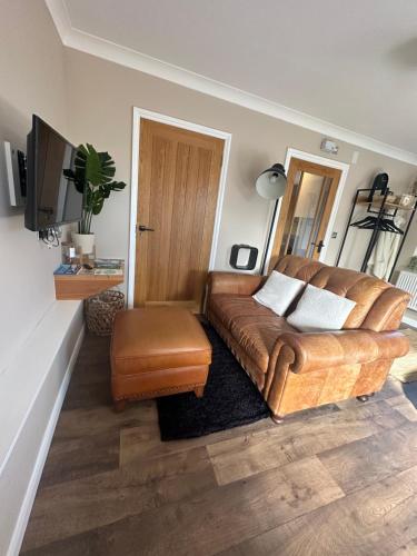 a living room with a leather couch and a television at The Cwtch,Self Contained Coastal Annex Freshwater in Freshwater