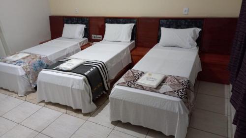 um quarto com três camas com lençóis brancos em HOTEL MODERNO em São Paulo