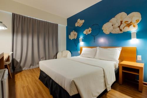 1 dormitorio con 1 cama grande y pared azul en ibis Styles Bauru, en Bauru