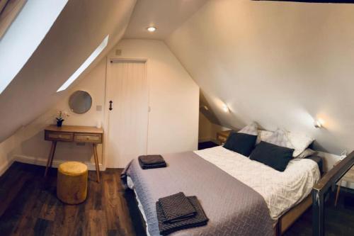 um quarto com uma cama e uma secretária num sótão em Little House Annexe em Shotteswell